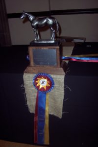 The championship trophy and one of the tricolor first place ribbons the team received for their Nationals win in May. (Photo by Liz Crumbly)